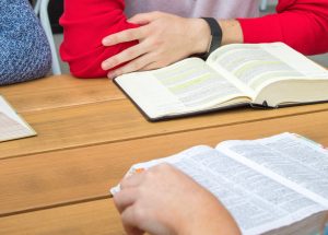 Young man with open Bible at table with other open Bibles
