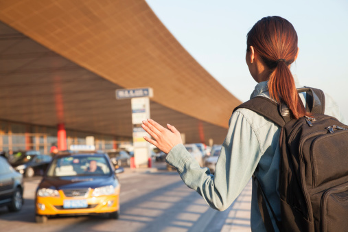 Young traveler hailing a taxi at airport